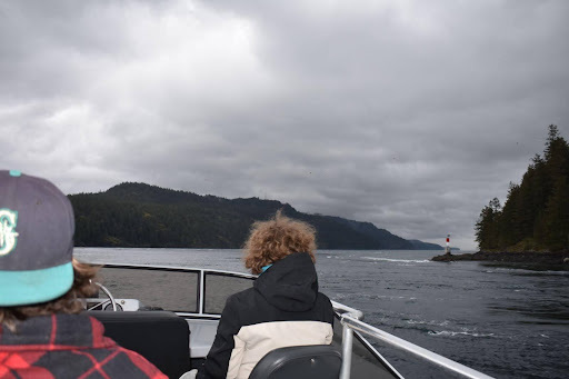Deux élèves sont assis sur un bateau et regardent l'eau et le rivage au loin.