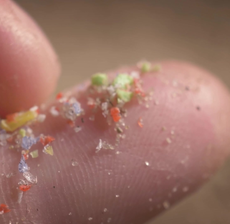 Image de micro plastiques colorés sur un doigt.