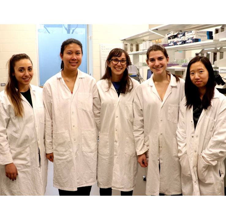 Chelsea Rochman et quatre élèves en sarrau blanc sourient à la caméra dans un laboratoire.
